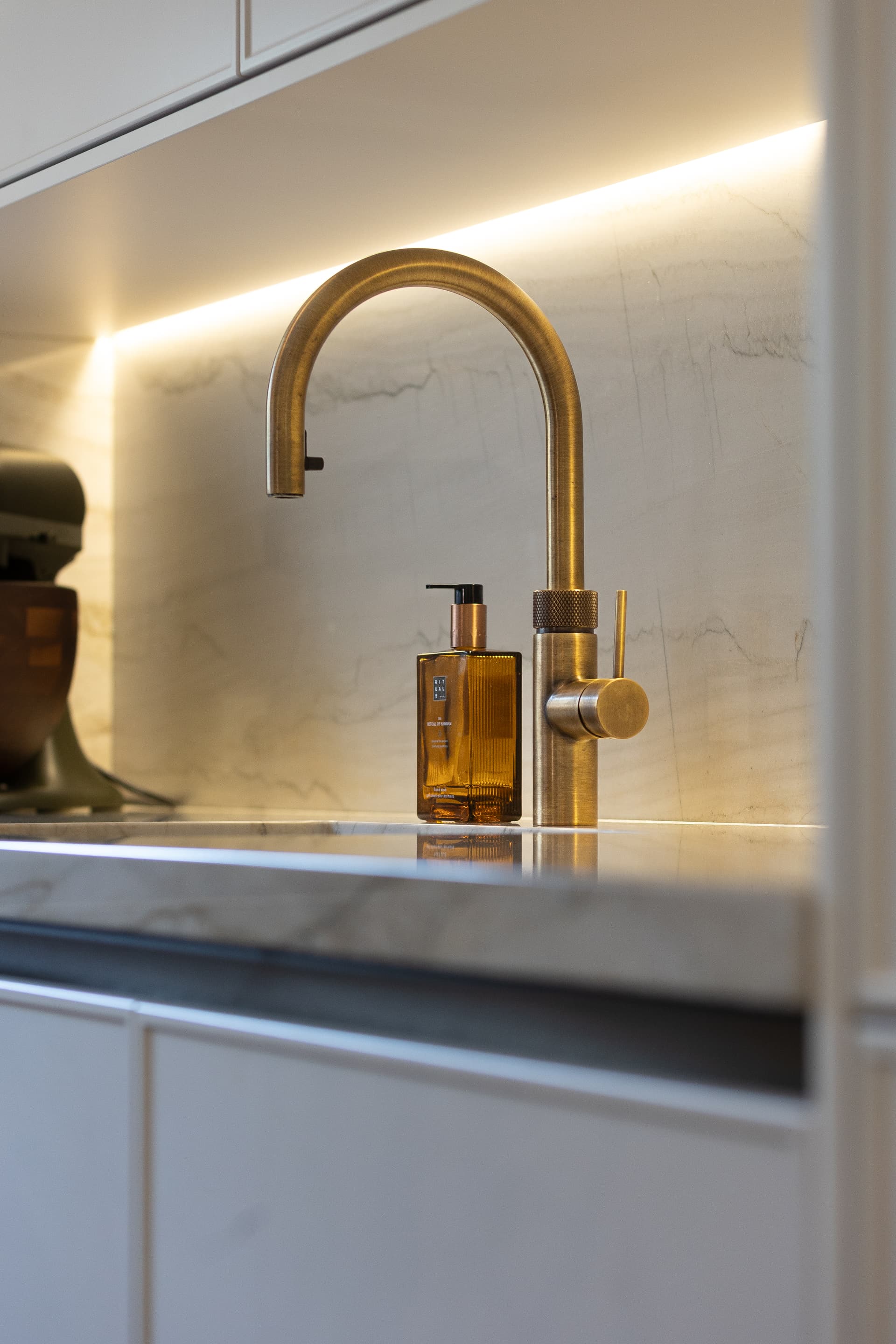 Beige keuken met wit marmer werkblad en een goude kraan