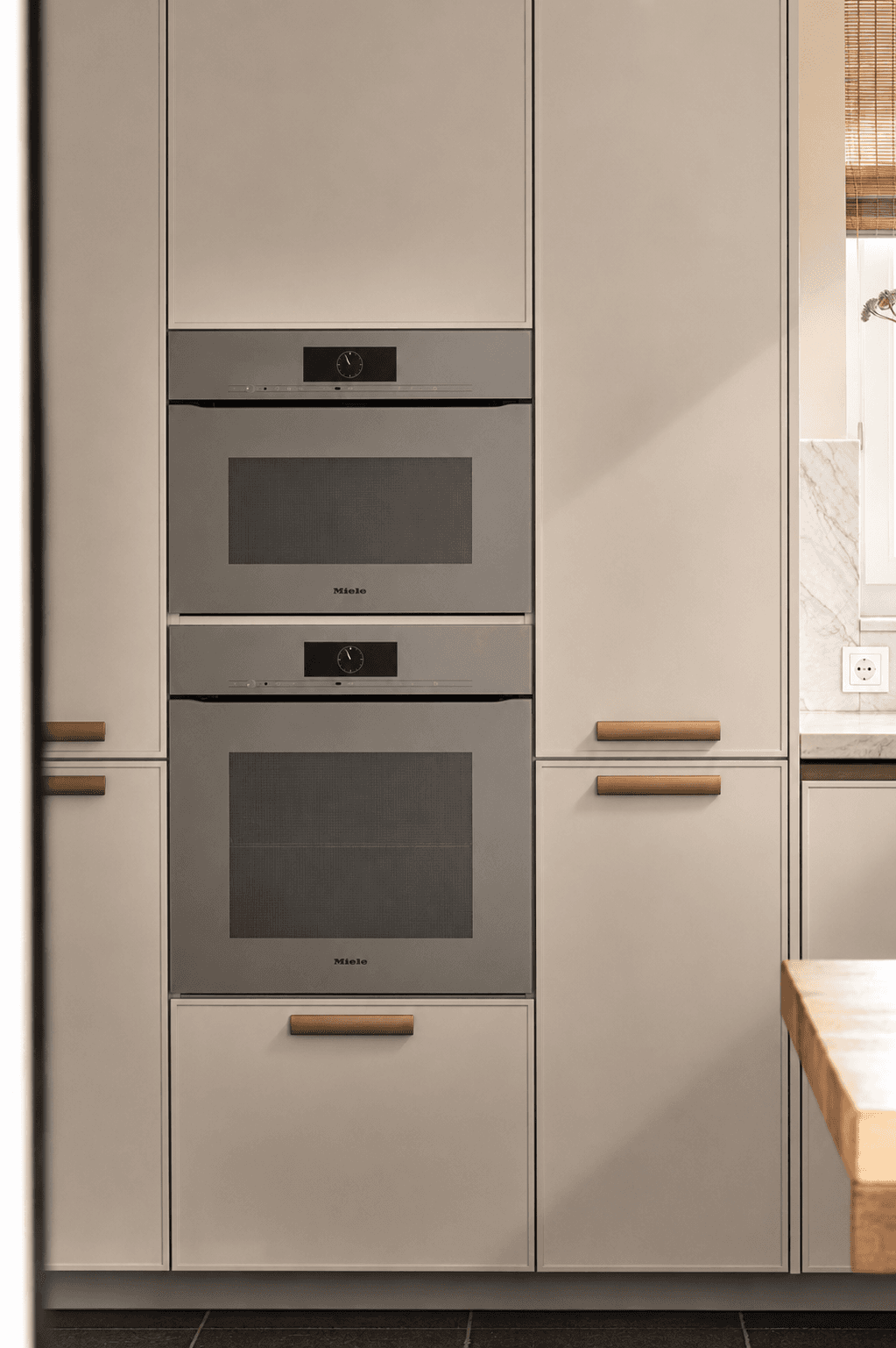Beige hoge keukenkasten met twee beige ovens en houten grepen