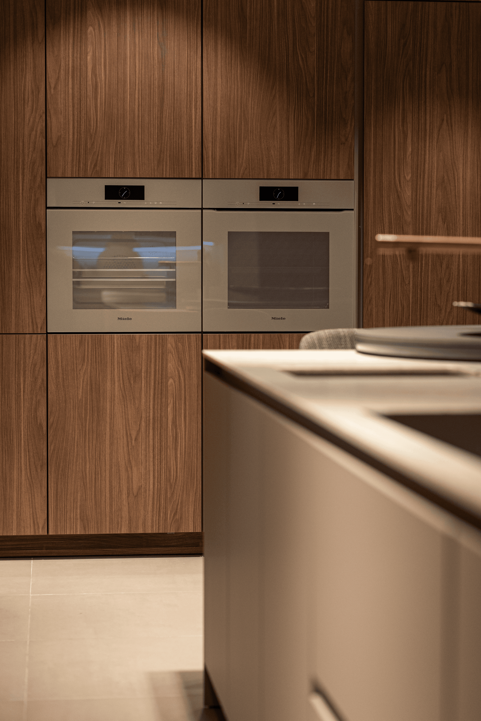 Donker houten hoge keukenkasten met twee beige ovens naast elkaar